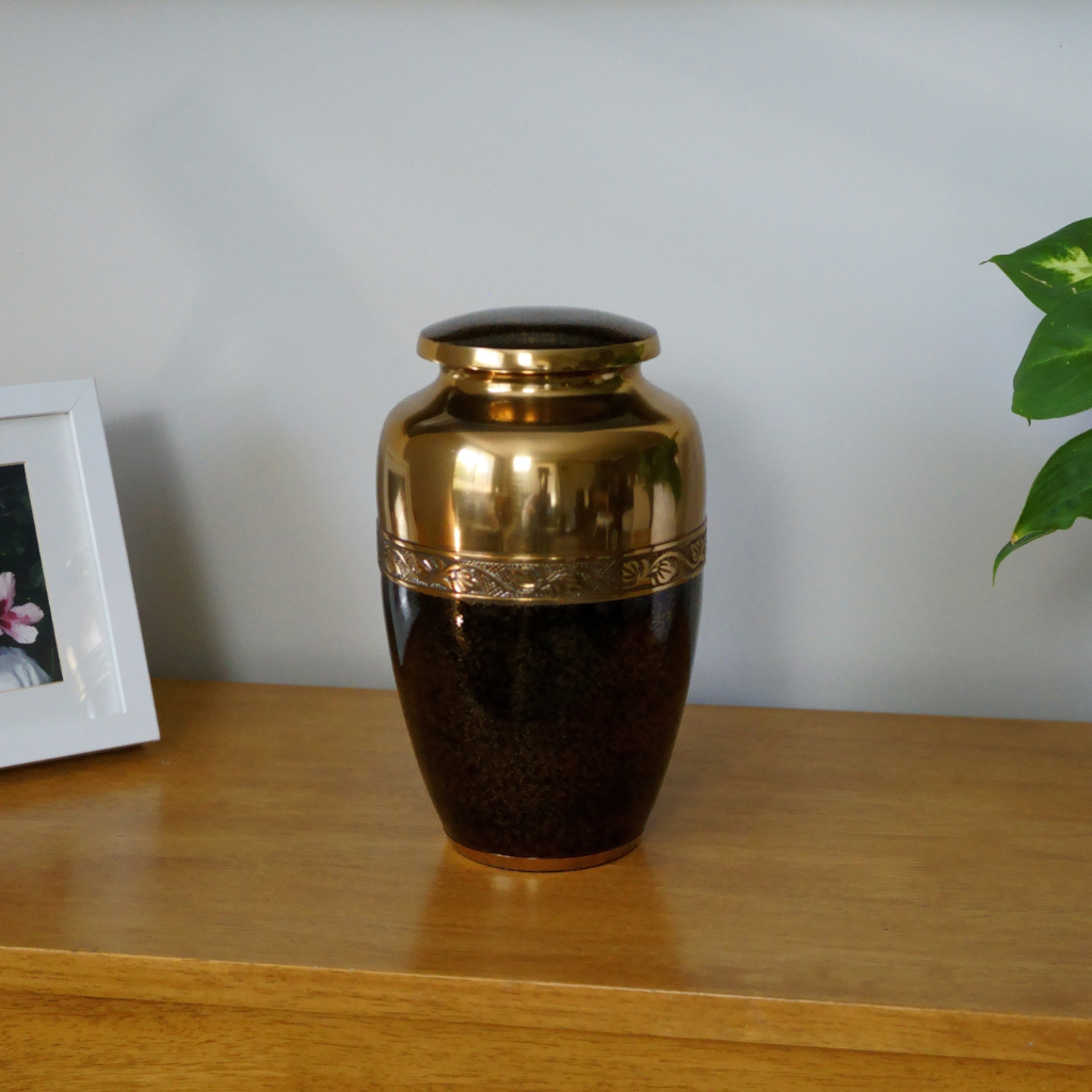 Bronze coloured aluminium urn with black speckled details on the bottom half in natural setting