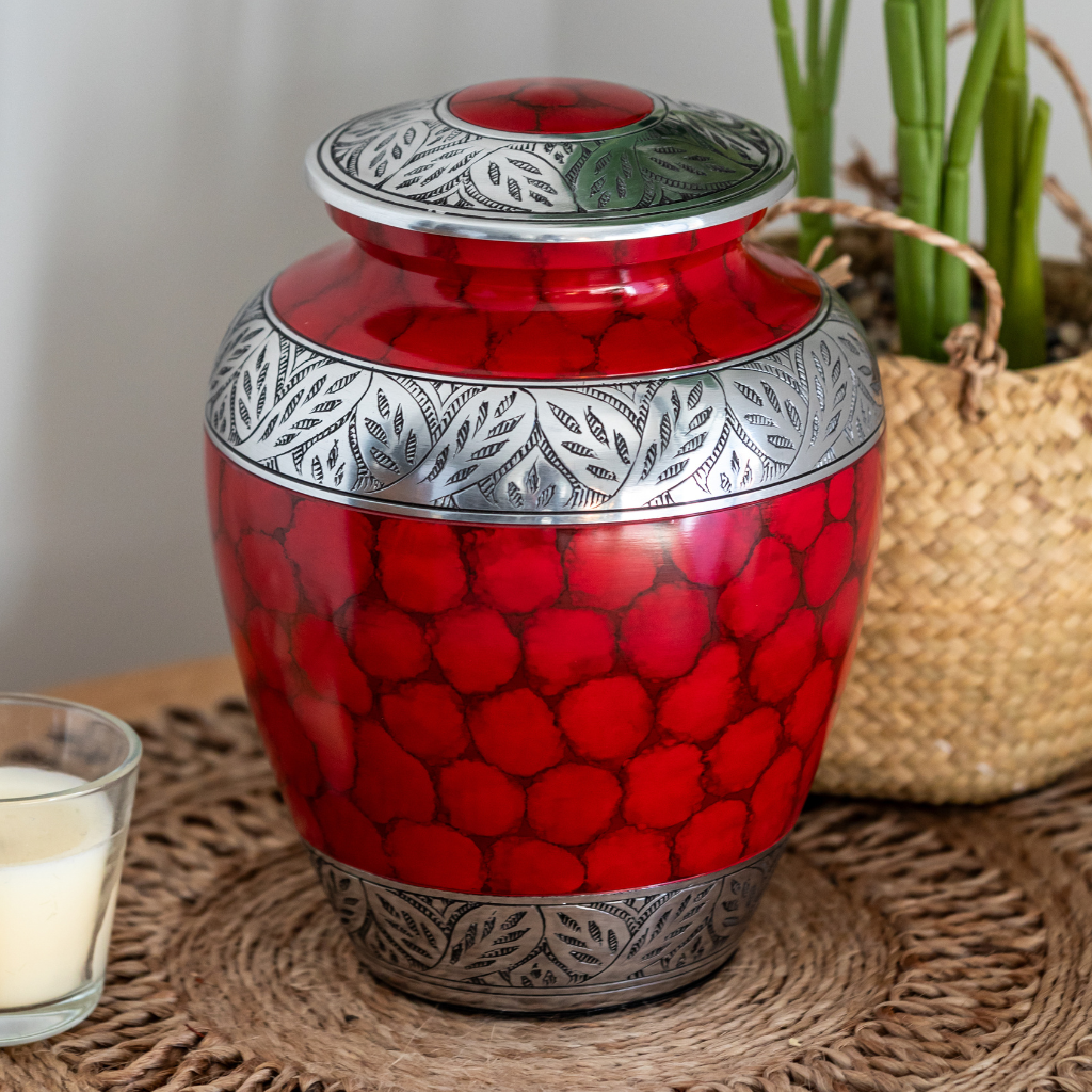 Red urn with soft scale details and silver leafy accents in natural setting