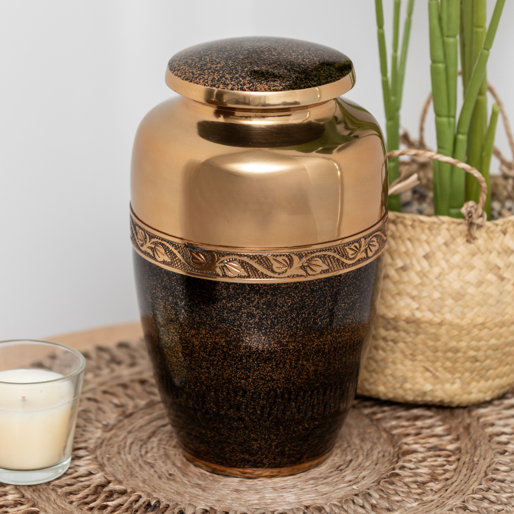 Bronze coloured aluminium urn with black speckled details on the bottom half in natural setting